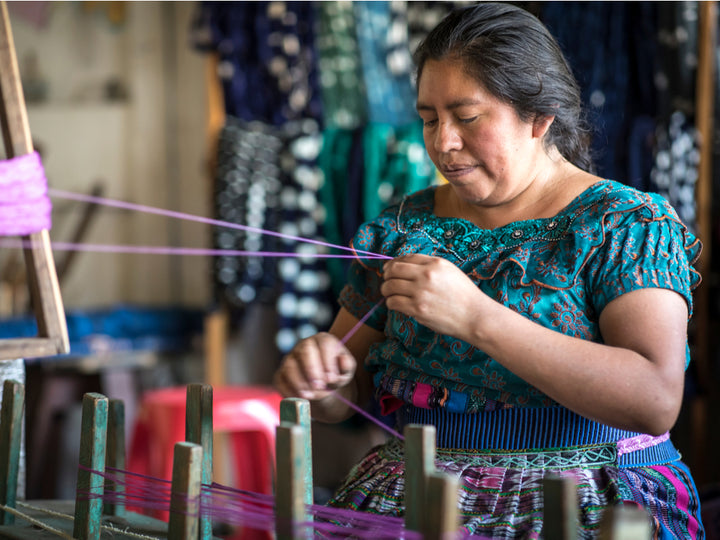 Mayan artisan sewing colorful clothing sold by Ta'Shi
